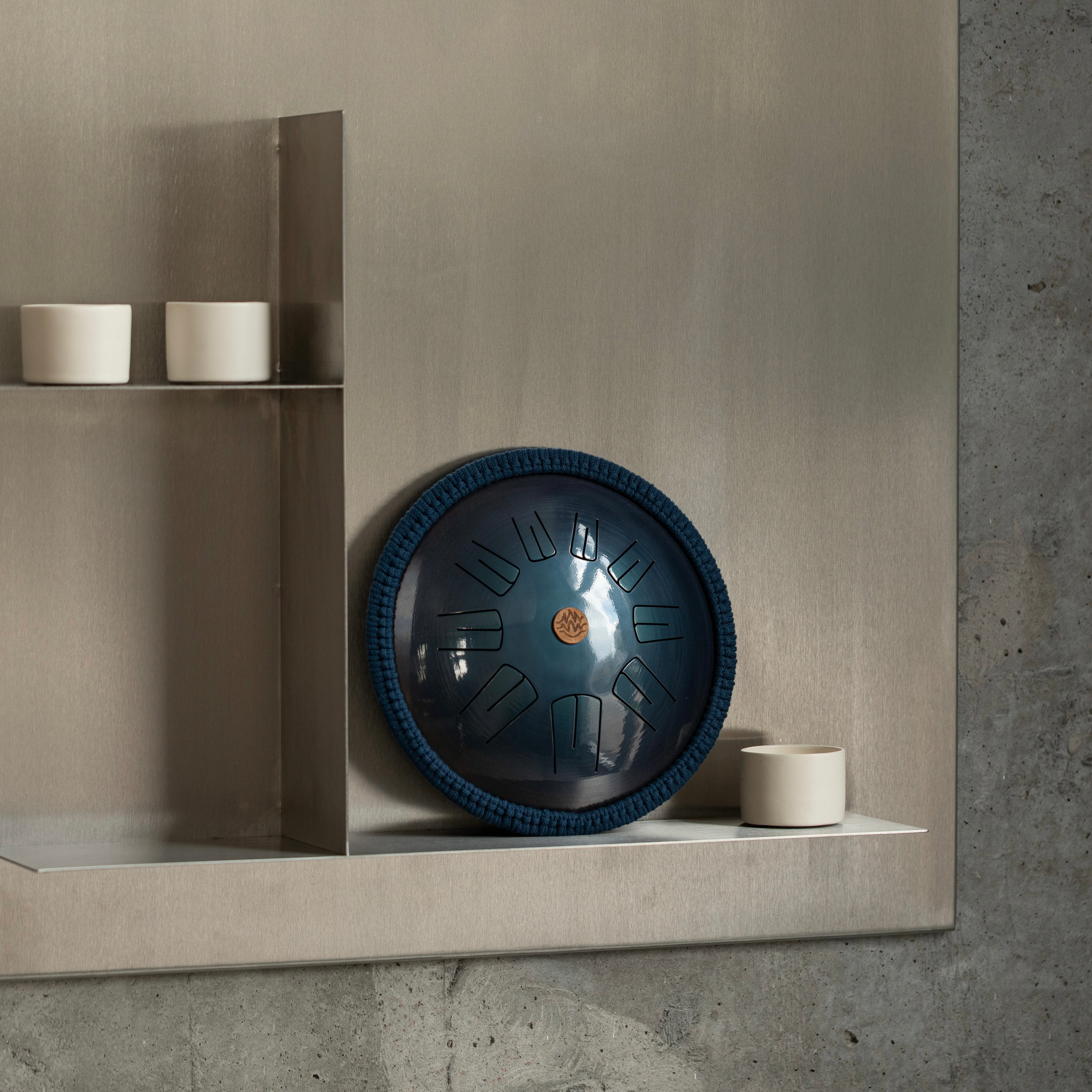 Steel tongue drum Spark model by Burning27 stands on a shelf against a light wall in a cozy yoga studio