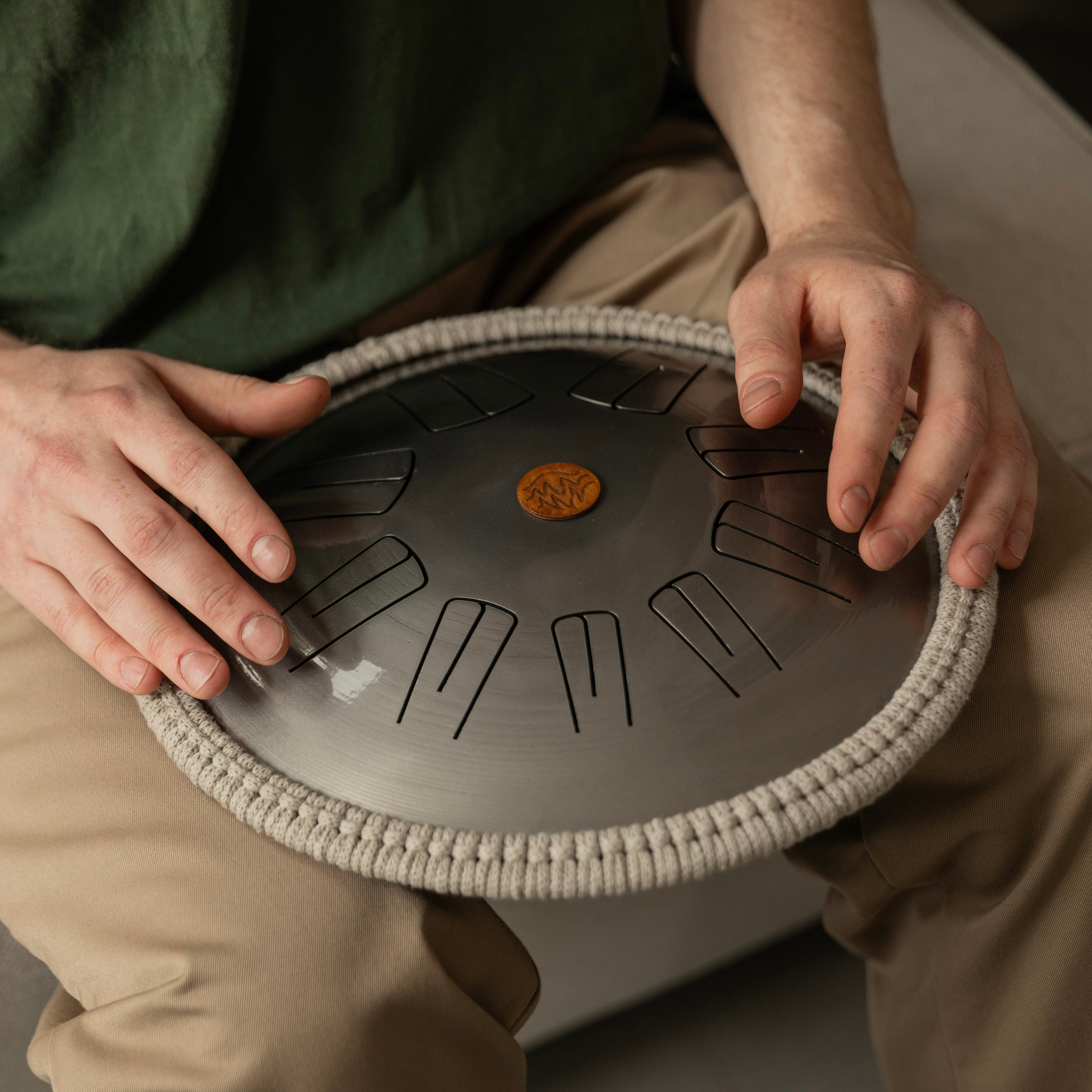 Person playing Spark steel tongue drum in cozy interior