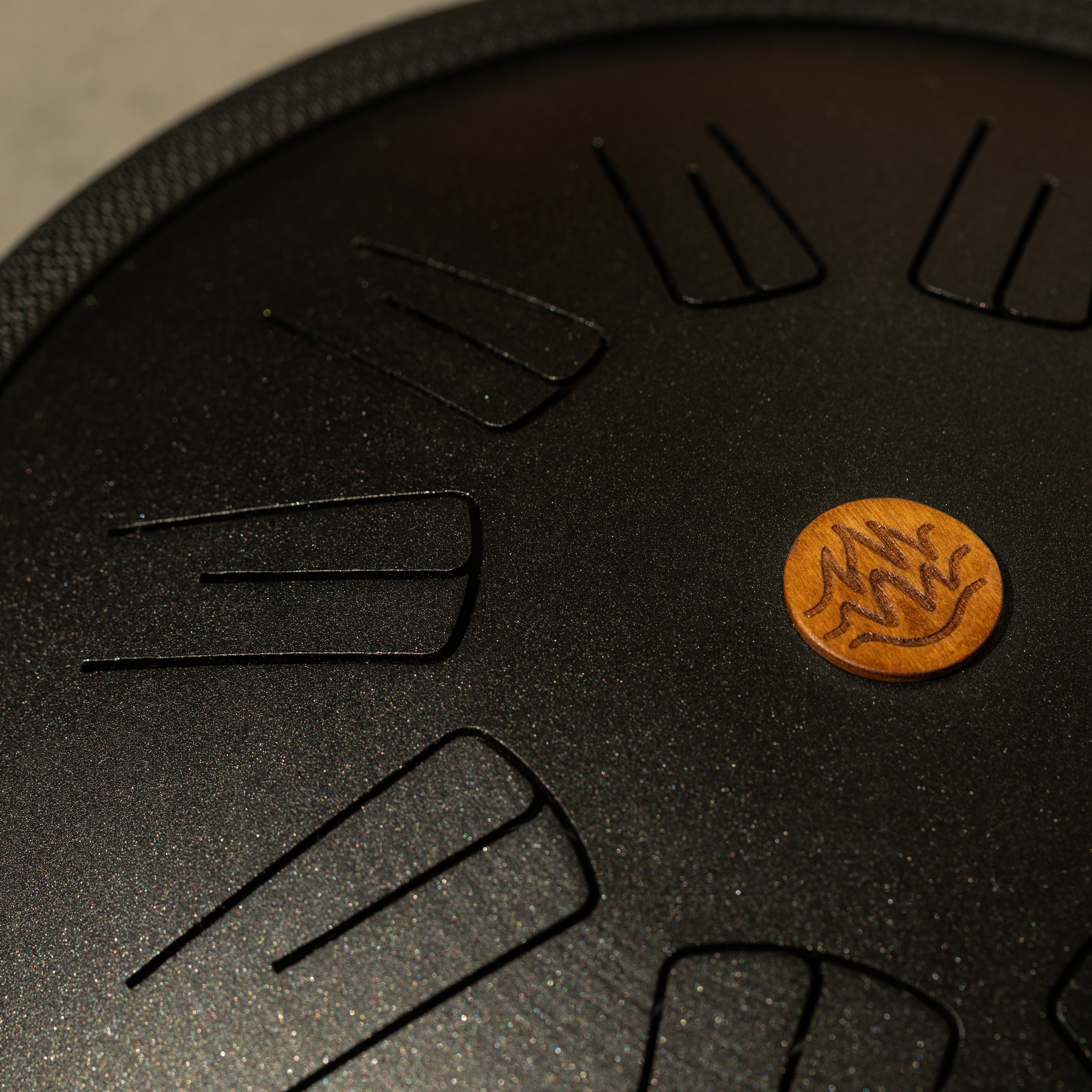 Close-up of a black color tongue drum with a small wooden logo design