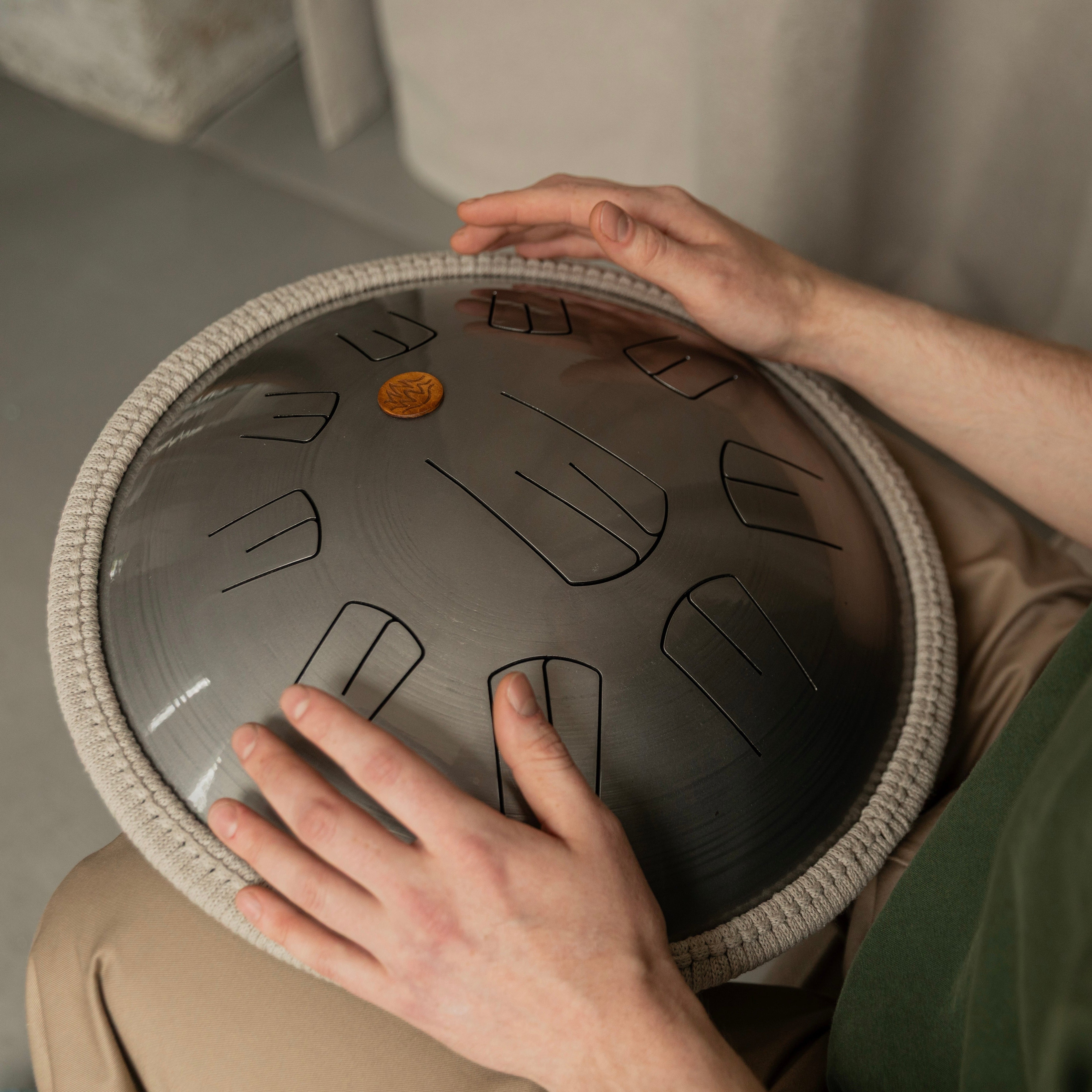 Person playing Ember steel tongue drum with a neutral background