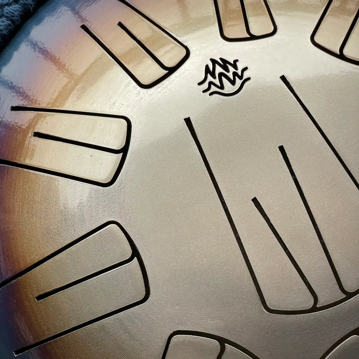 Close-up view of a steel tongue drum Spark V2 model, with cutouts petals and a small flame-like Burning27 logo near the top center.