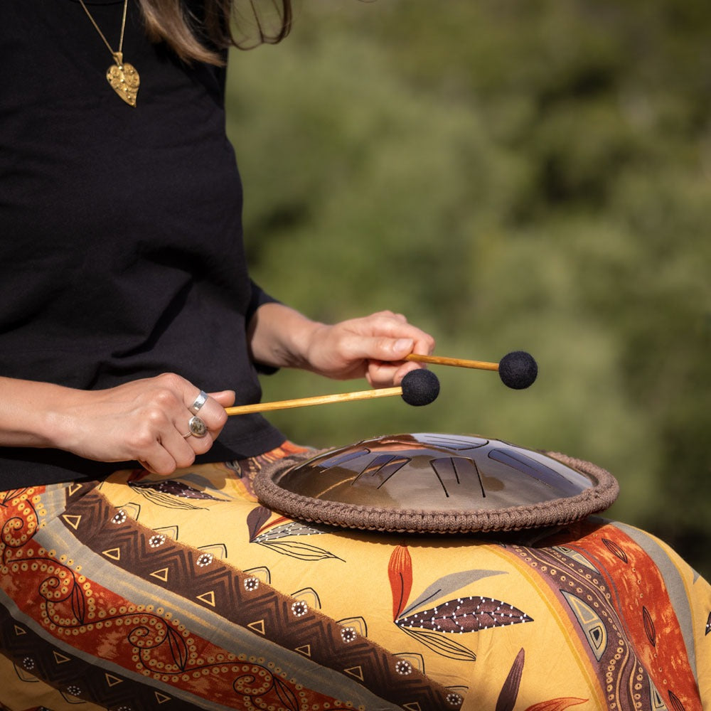 A person meditates by playing with mallets on a Spark V2 steel tongue drum by Burning27