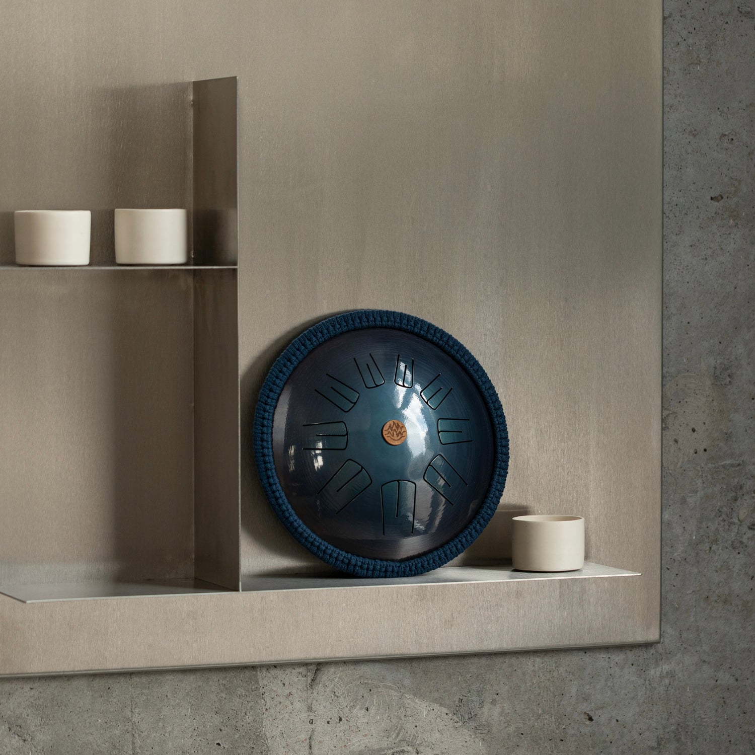 Steel tongue drum Spark model by Burning27 stands on a shelf against a light wall in a cozy yoga studio 